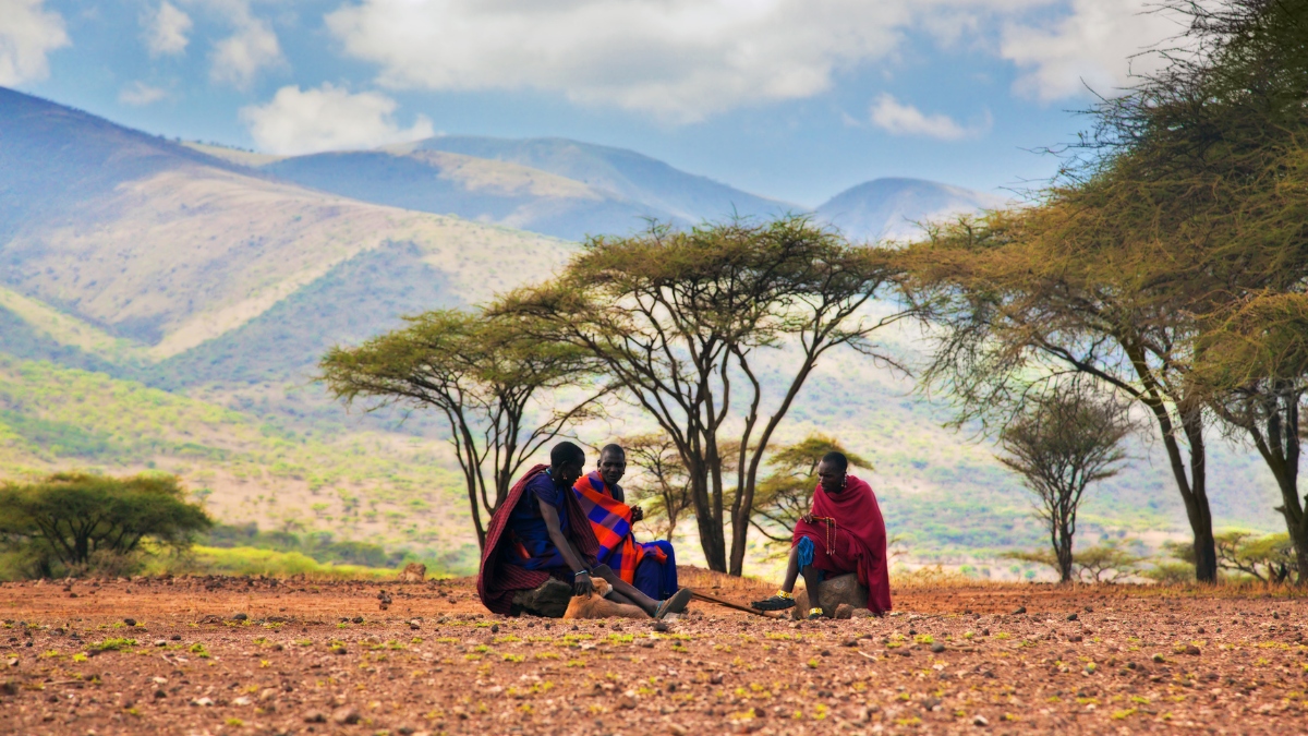 Maasai elder speaking with guests in a quiet conservancy setting.